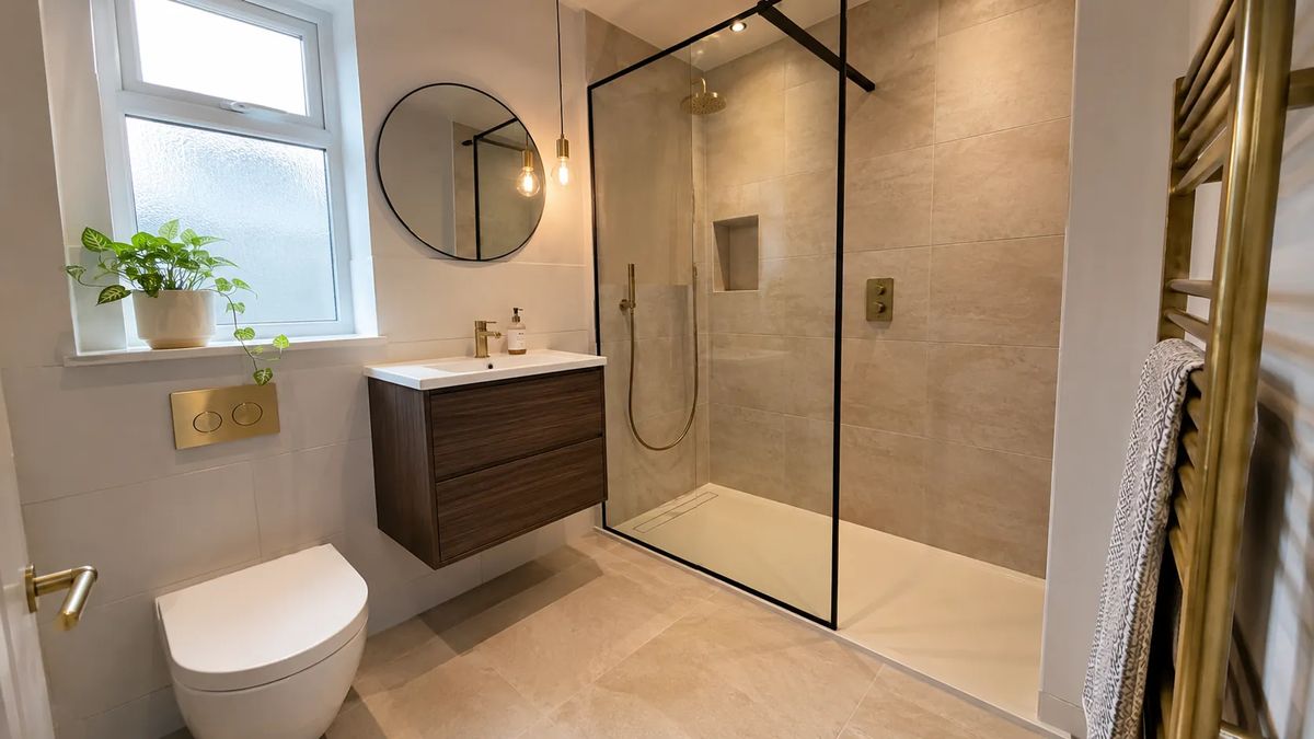 A walk-in shower room with stone-effect tiles and brass fittings